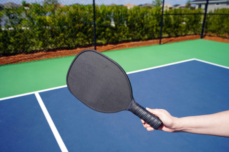 Hand holds pickle ball paddle